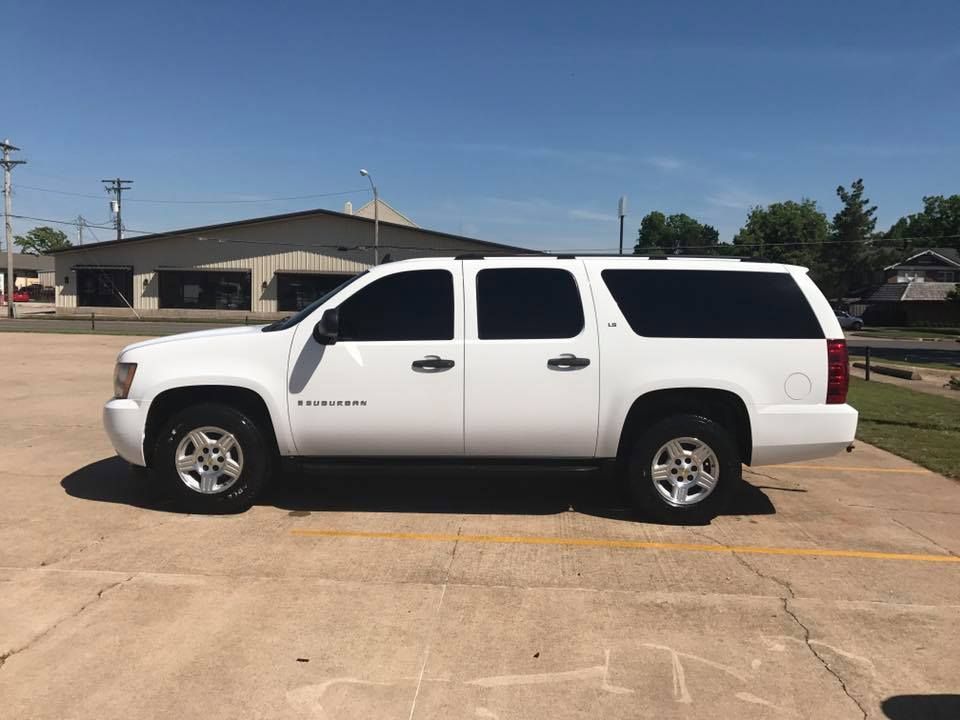 White SUV parked in a lot beside a low building under a clear blue sky
