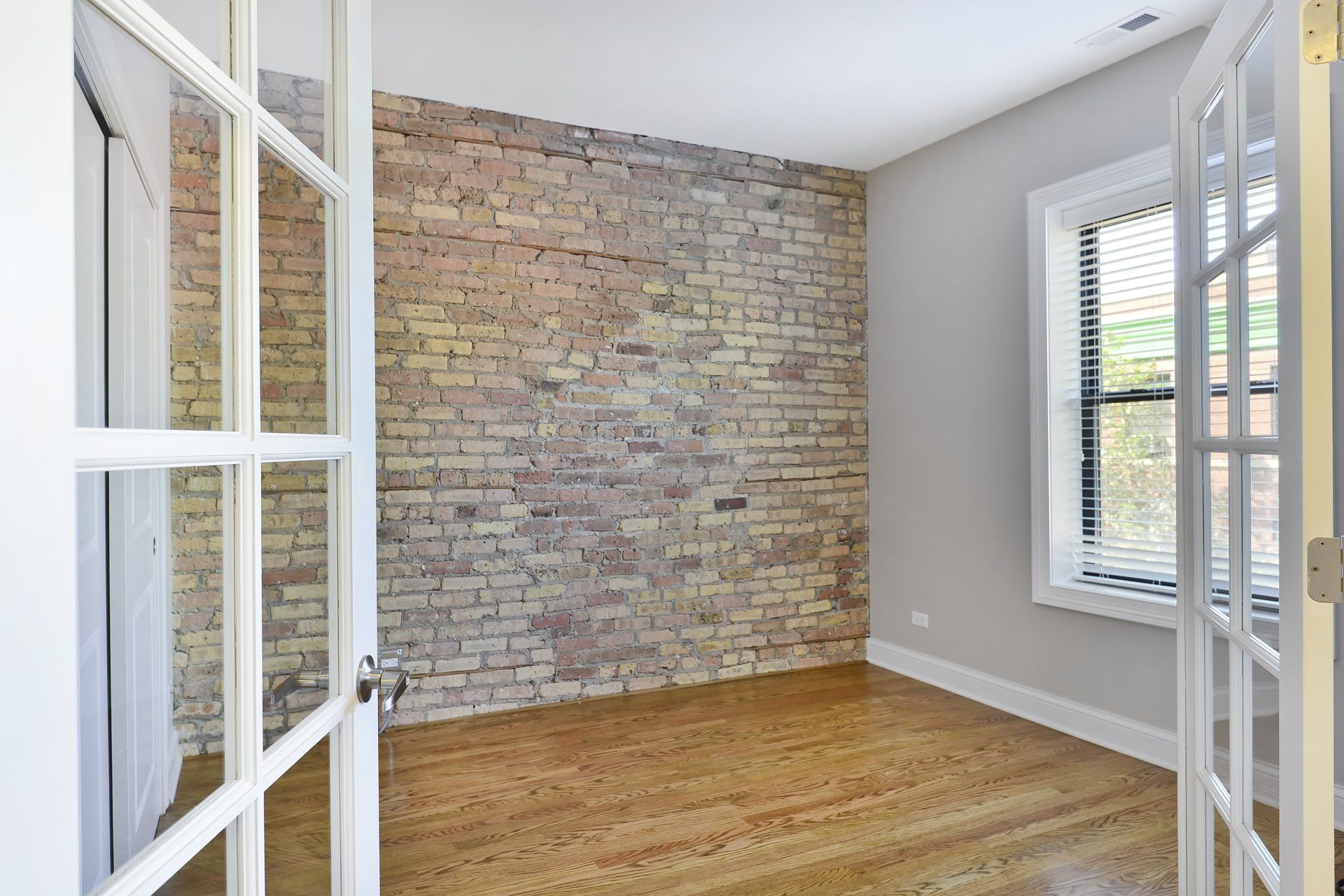 Apartment bedroom with brick wall and window at The Belmont by Reside Flats.