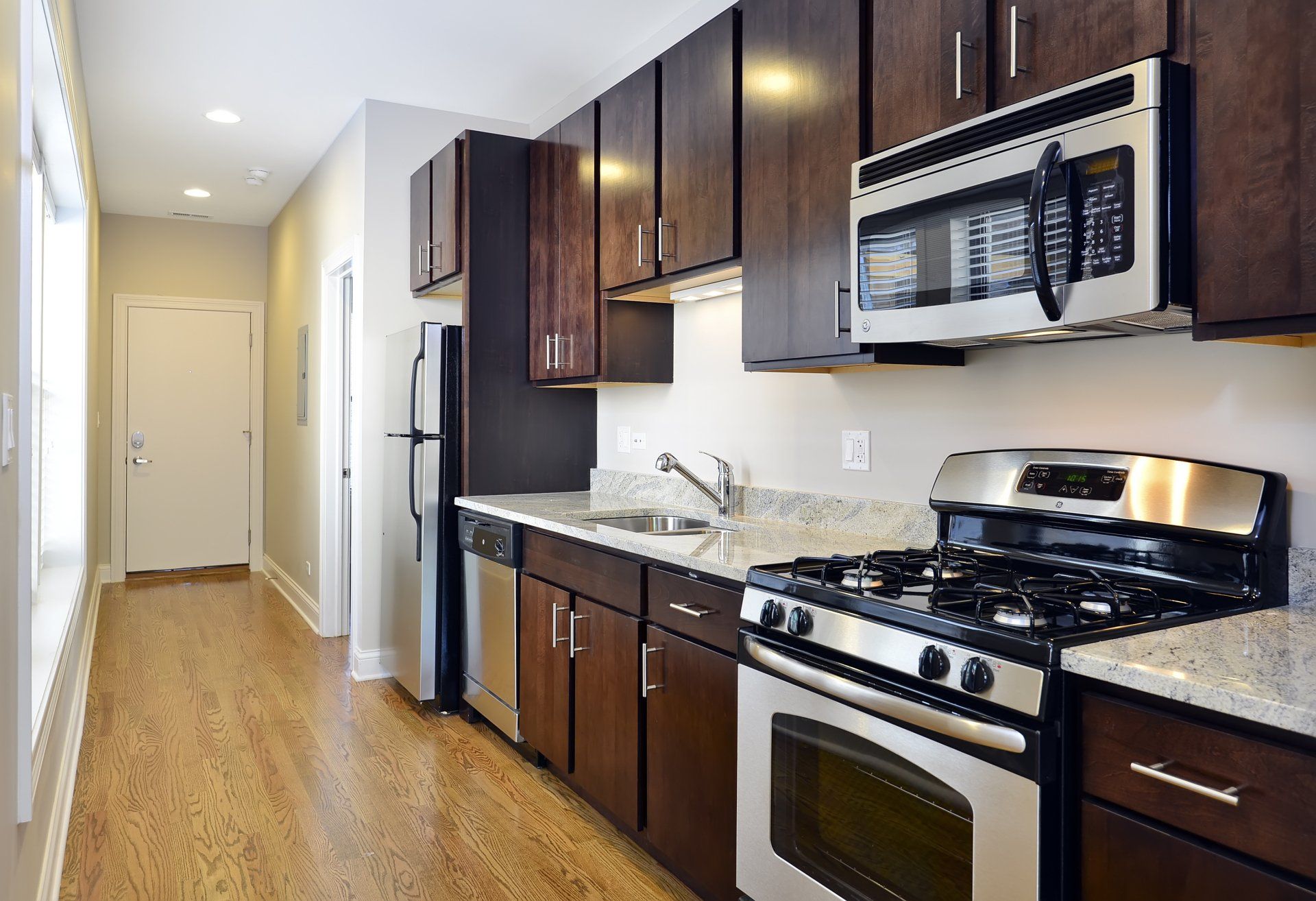 A kitchen with stainless steel appliances and wooden cabinets at The Belmont by Reside Flats.