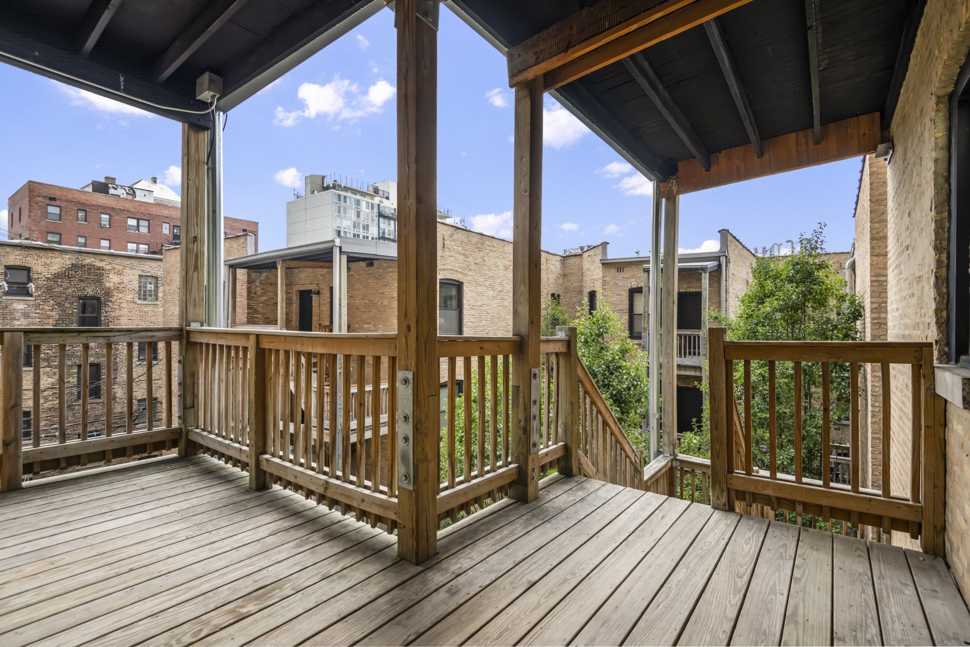 An empty deck with a wooden railing and a view of a city.