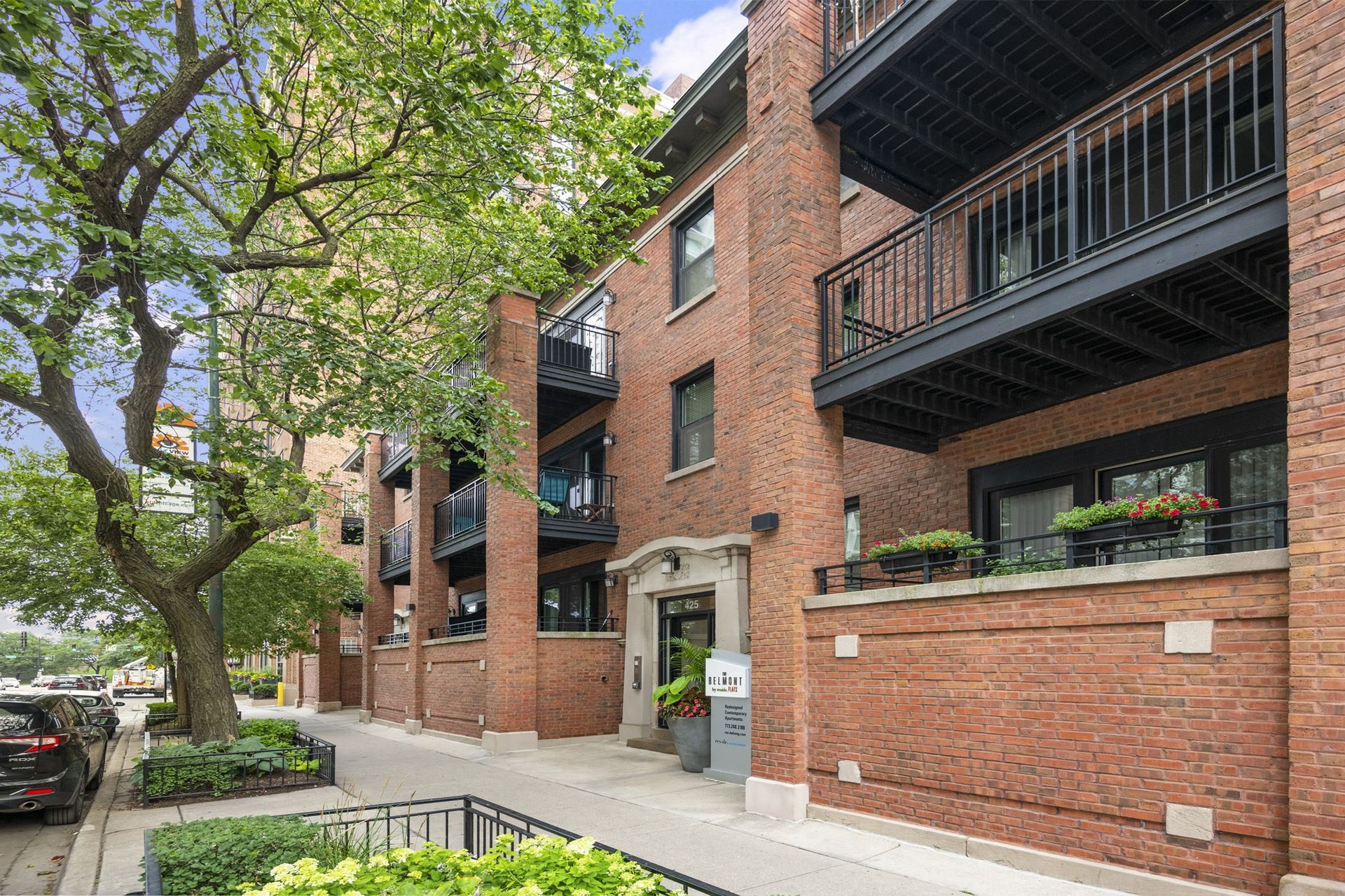 the apartment building has a red brick facade and a balcony