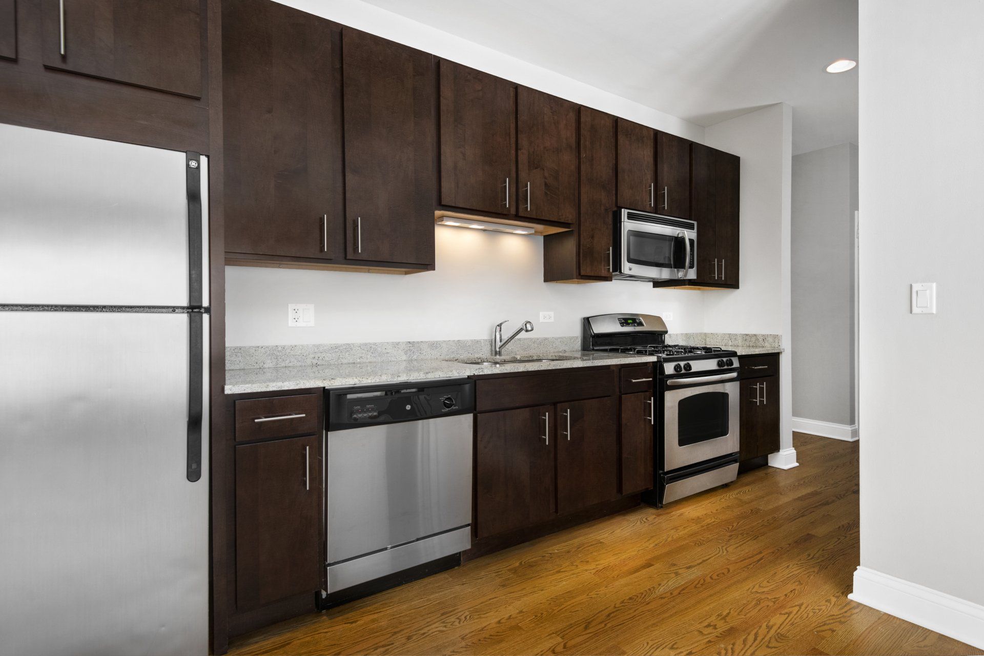 Modern kitchen with dark brown cabinets and silver appliances at The Belmont by Reside Flats.
