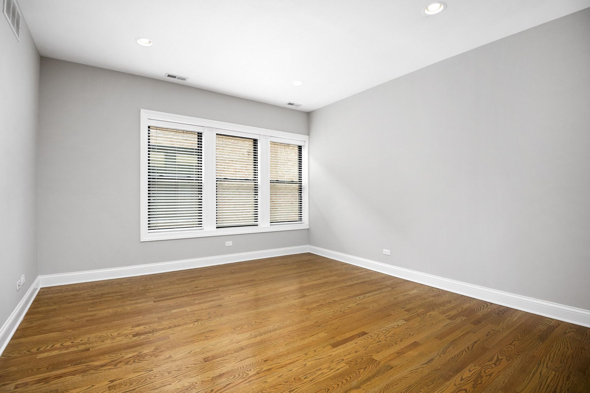 an empty living room with wood floors and a window