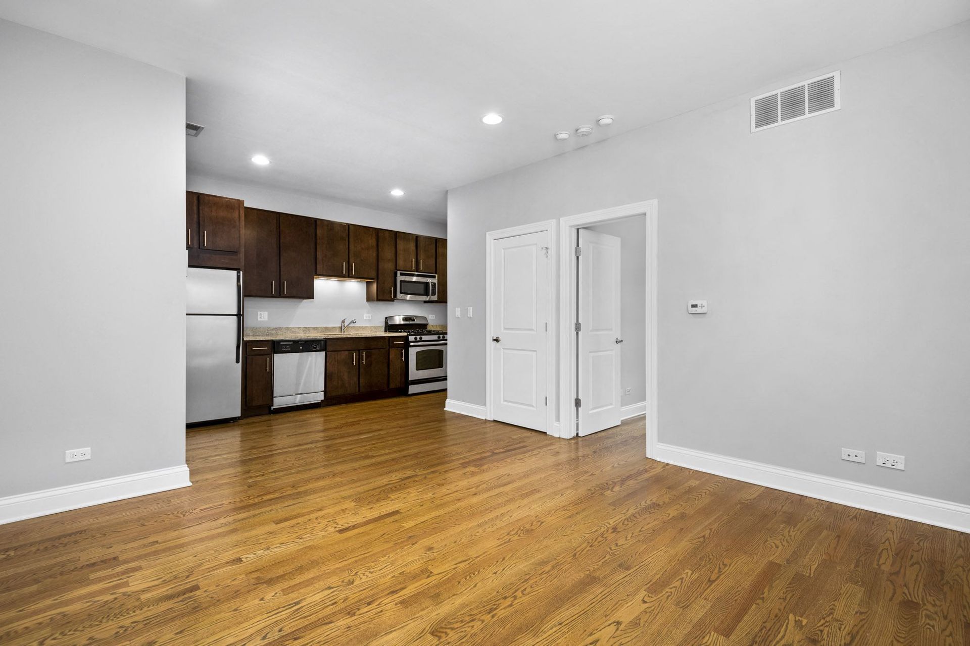 a renovated living room and kitchen with white walls and wood floors