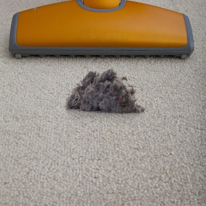 A vacuum cleaner is cleaning a pile of dust on a carpet.
