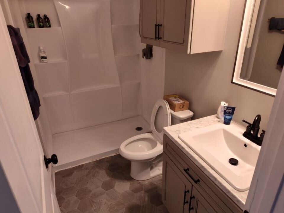 A bathroom with a toilet , sink and shower.
