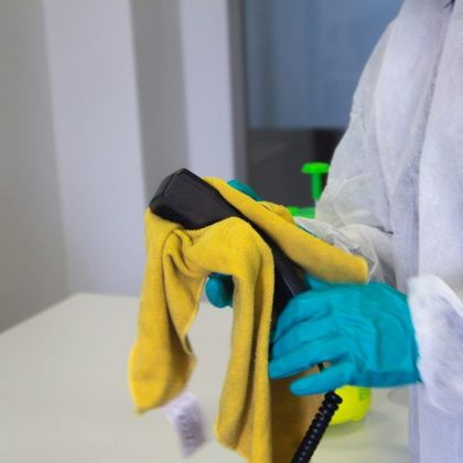 A person wearing blue gloves is cleaning a phone with a yellow towel.