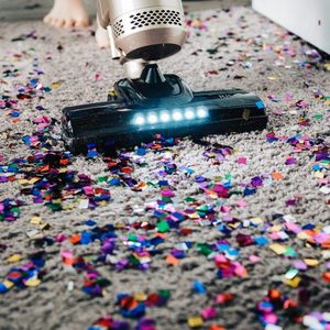 A vacuum cleaner is cleaning a carpet covered in confetti.