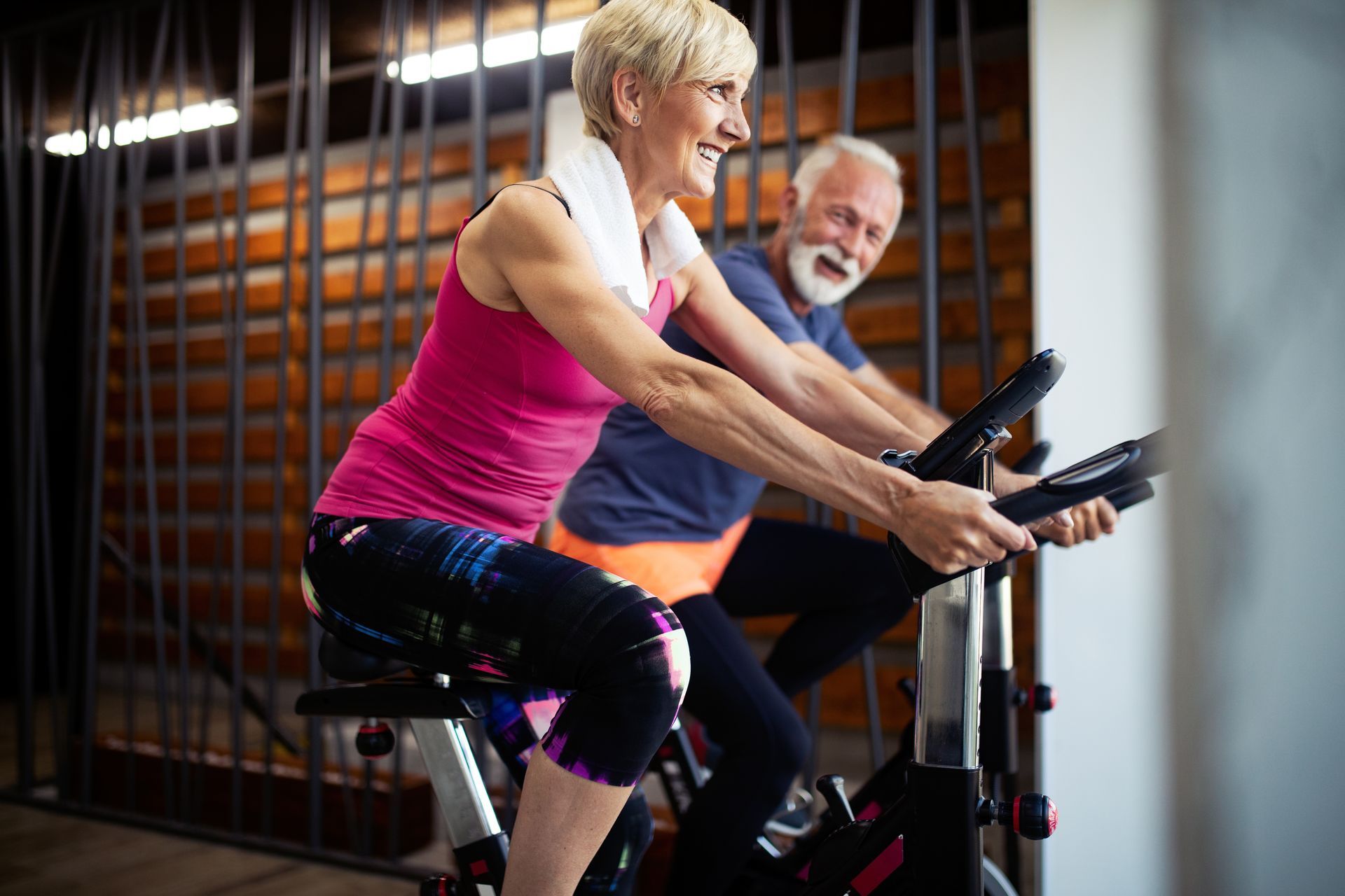 A mature senior couple exercising on stationary bicycles near Lexington, Kentucky (KY)