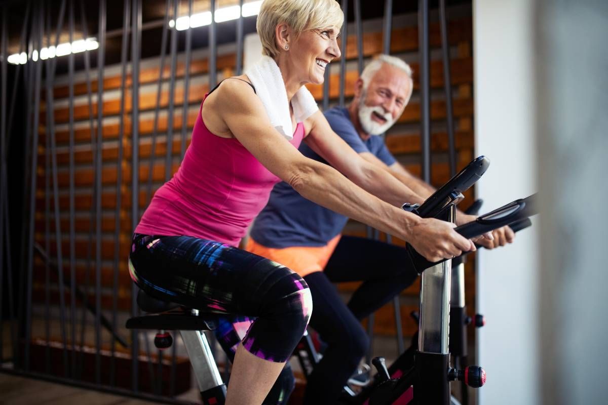 A mature senior couple exercising on stationary bicycles near Lexington, Kentucky (KY)