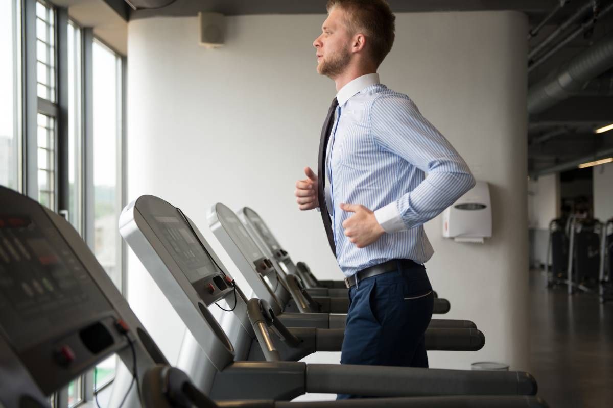 A businessman in office attire jogging on a treadmill near Lexington, Kentucky (KY)