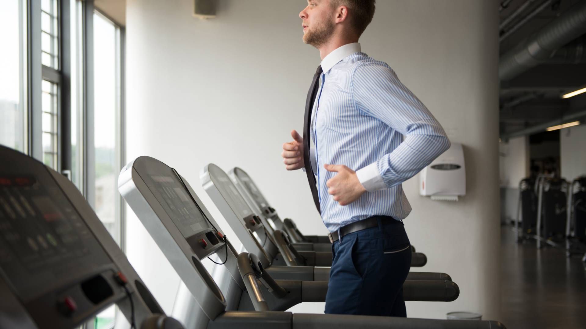 A businessman in office attire jogging on a treadmill near Lexington, Kentucky (KY)