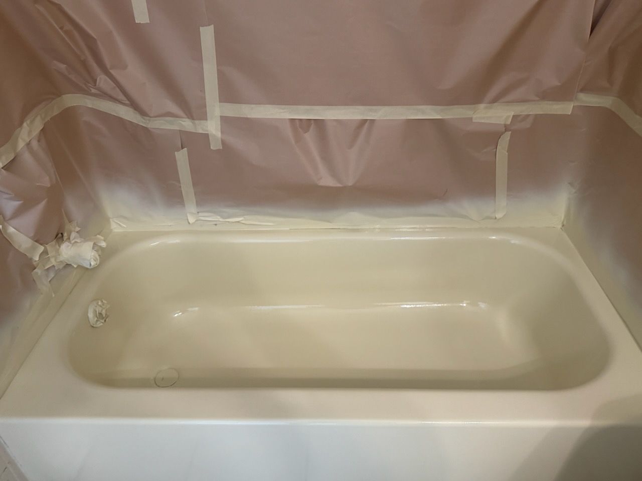 Bathroom tub covered in plastic sheeting, likely during renovation or painting.