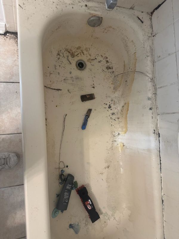 Dirty white bathtub with scattered tools and debris inside