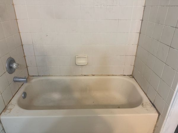 Empty white bathtub with tiled walls and chrome faucet in a bathroom