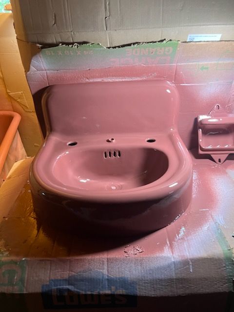 Pink toilet sink in a cardboard display setup, with spray paint and blue foam around it.