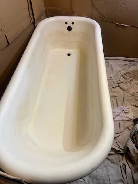 White bathtub with three faucet holes, shown in a partially finished bathroom.