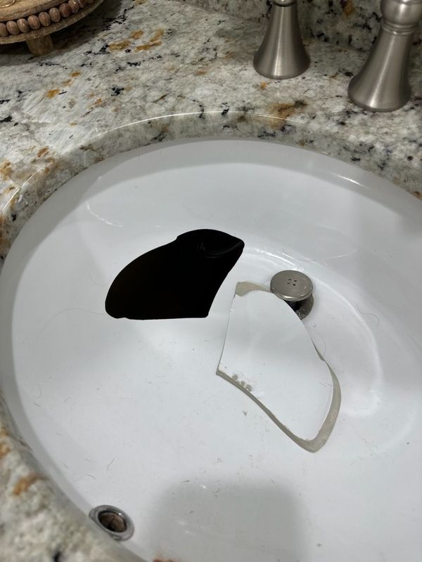 Broken black and white sink basin pieces in a bathroom countertop sink