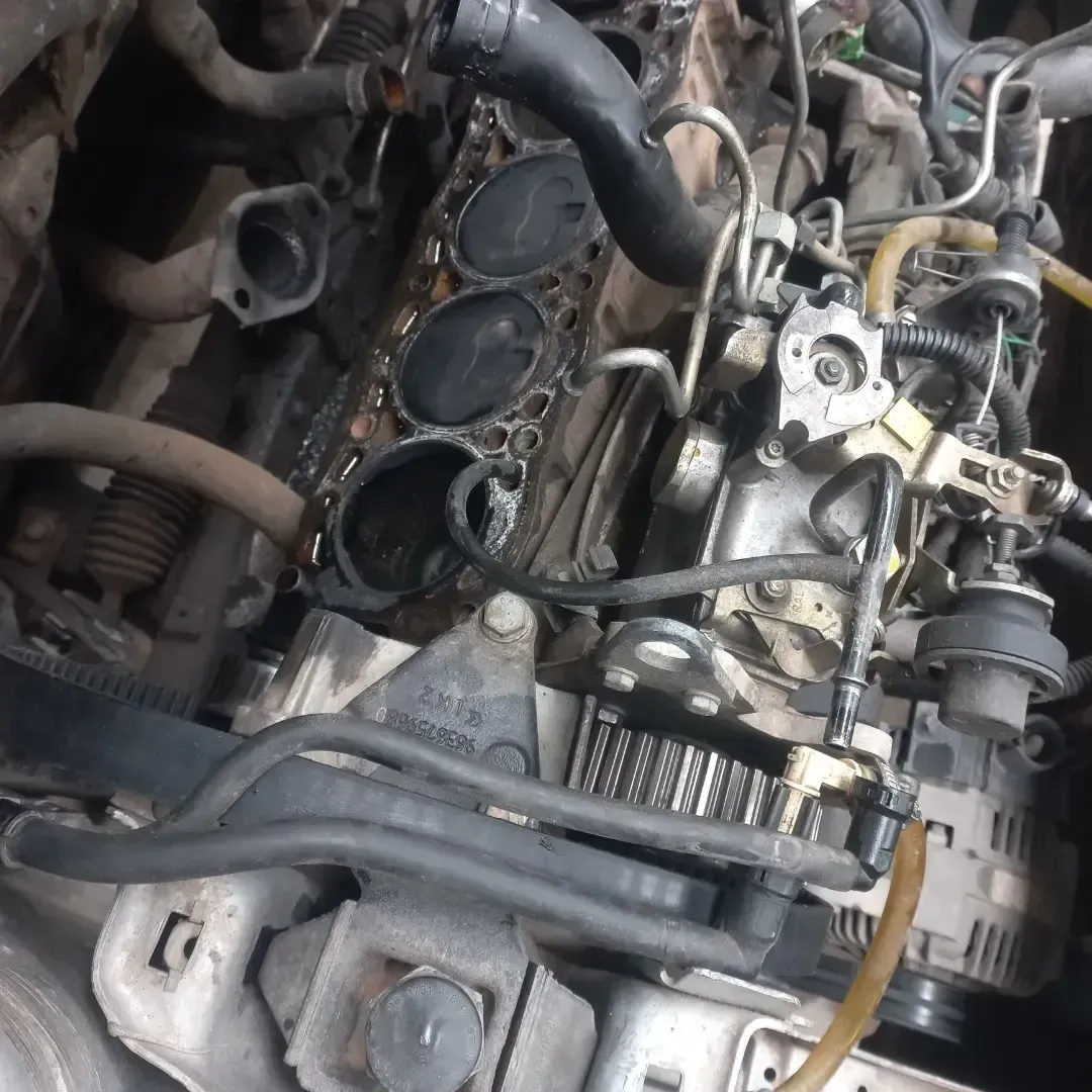 El bloque motor de un automóvil, abierto, dejando al descubierto los cilindros, los componentes internos y las diversas mangueras y conexiones de cableado.