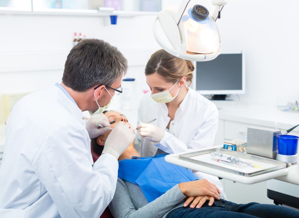 Dentist and assistant examining a patient's teeth in a dental office.