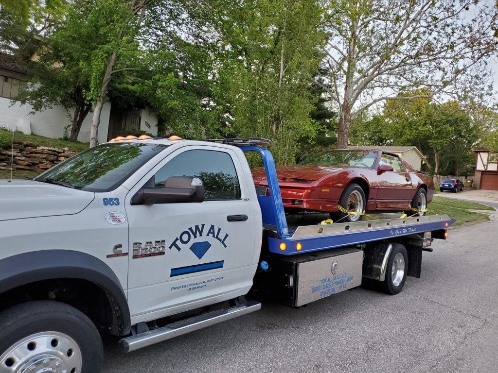 A red car is being towed by a tow truck.