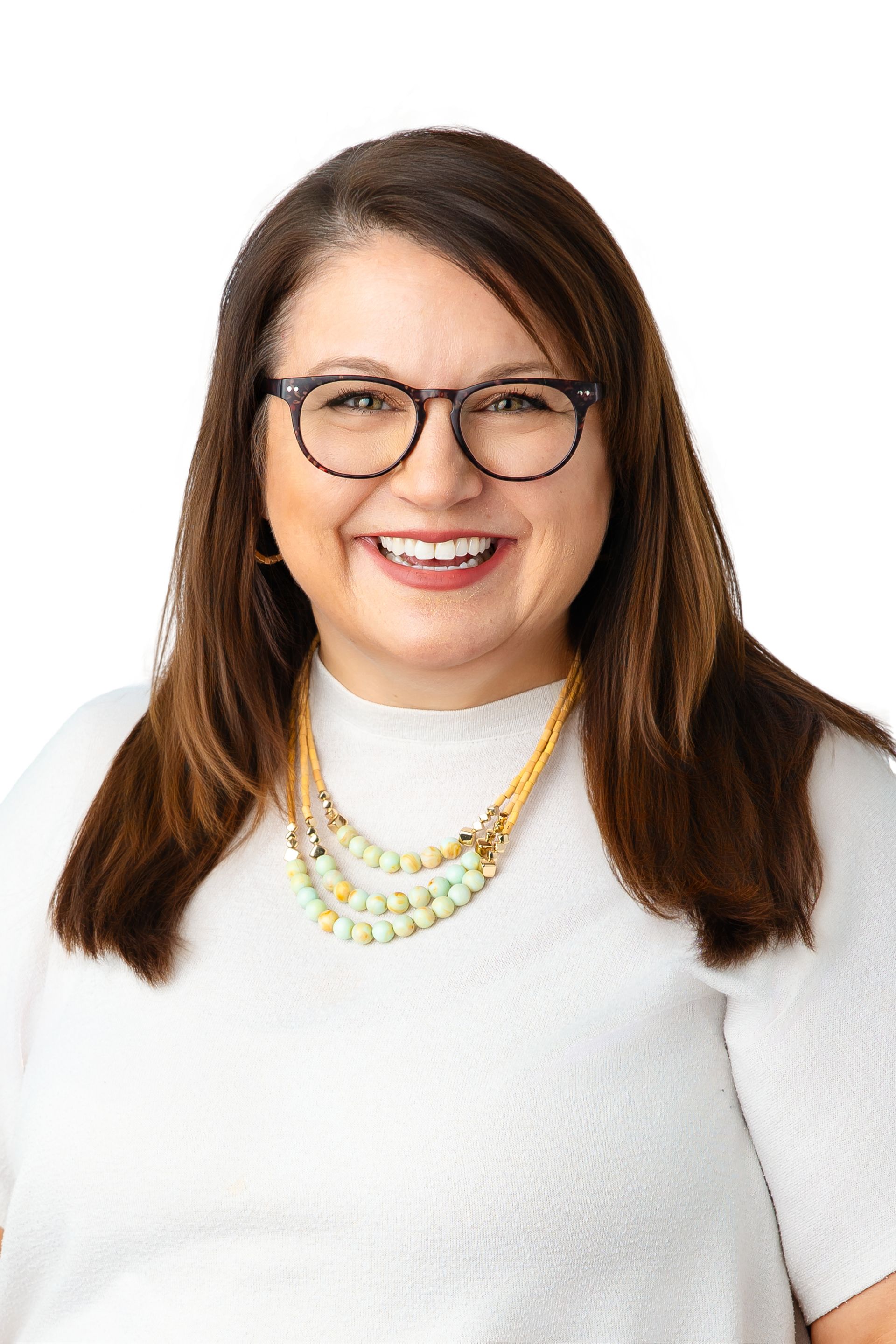 A woman wearing glasses and a necklace is smiling for the camera.