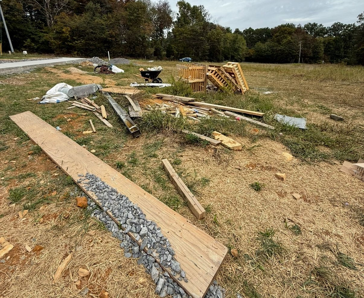 Pile of discarded furniture and appliances outdoors, including cabinets, stove, sink, and doors.