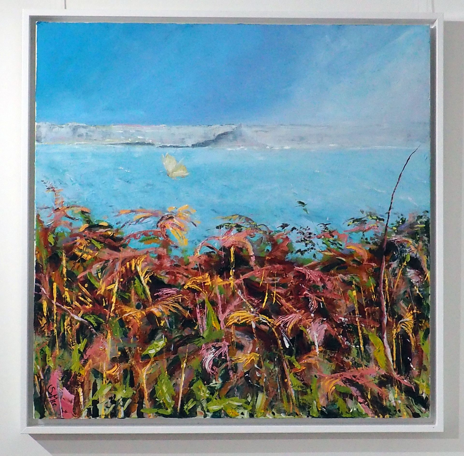 Square painting with orange / green bracken foreground. Above the light aqua sea sits a misty St Michael's Mount. Above is bright blue sky with light coming in from the top right corner. There is a Cabbage White Butterfly flying close above the bracken. Simply framed in white wood. 