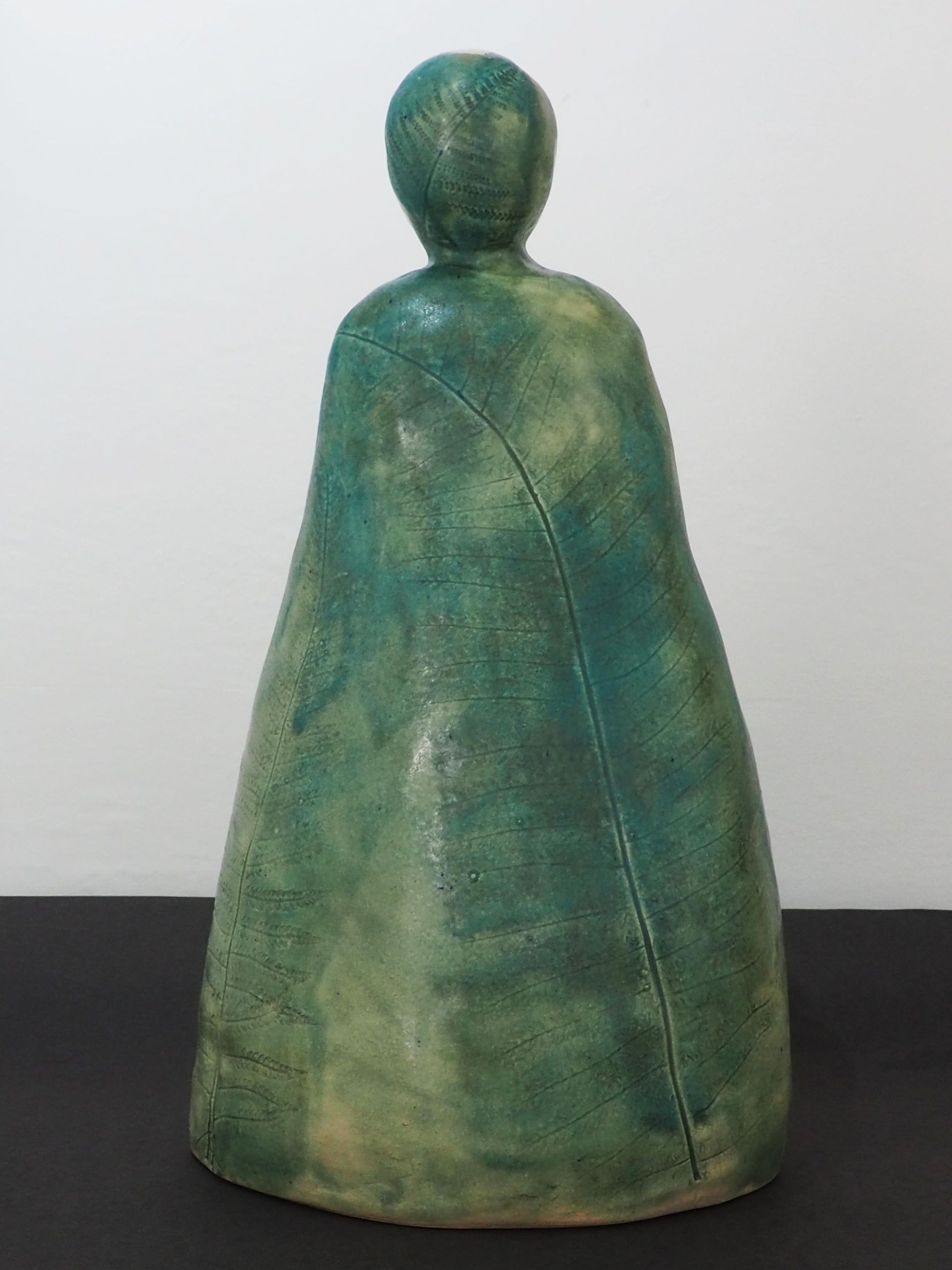 A ceramic simple green figure with a fern imprint.