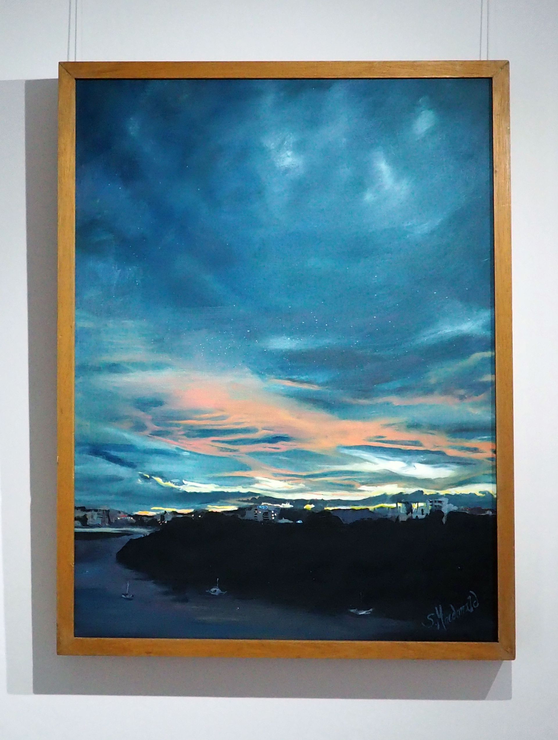 Portrait canvas of mainly a clouded sky during sunset. There is yellow light on the horizon and peach highlighted clouds with the majority of clouds dark blue. There is a headland with a river wrapped around - backlit by the sunset. Tiny boats and buildings.The sky mainly features. 