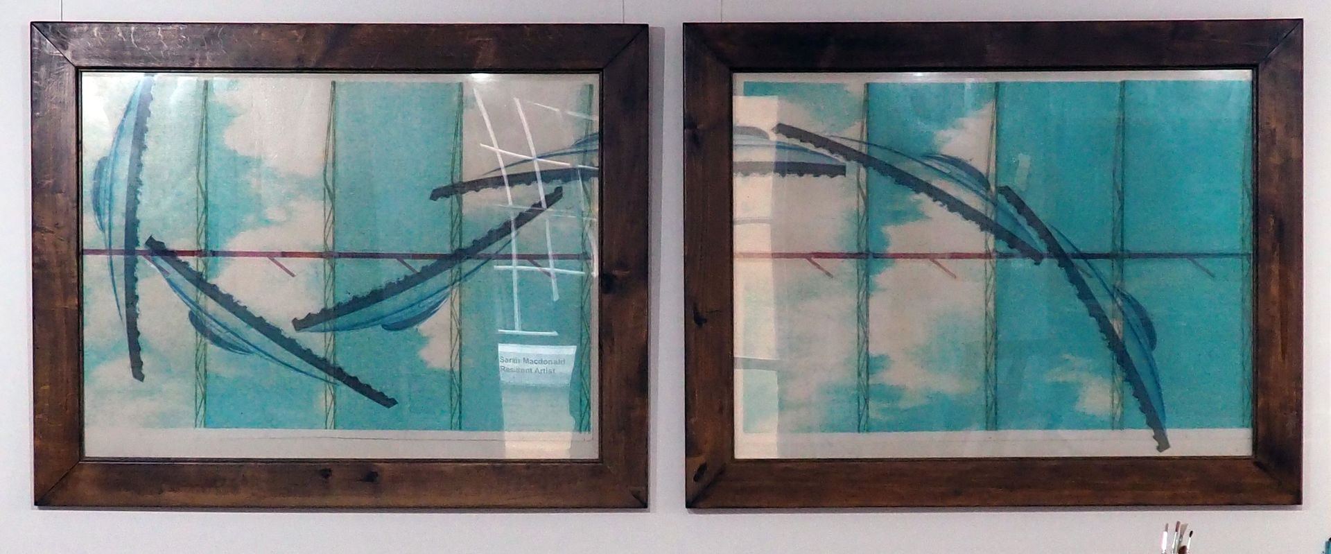 Photo taken of two large framed print-influenced pieces. The roof of the Roundhouse is repeated like a wave in dark blue, and flows from one frame into the other. There are signs of the elevated railway in red as well as the light blue sky as a backdrop.
