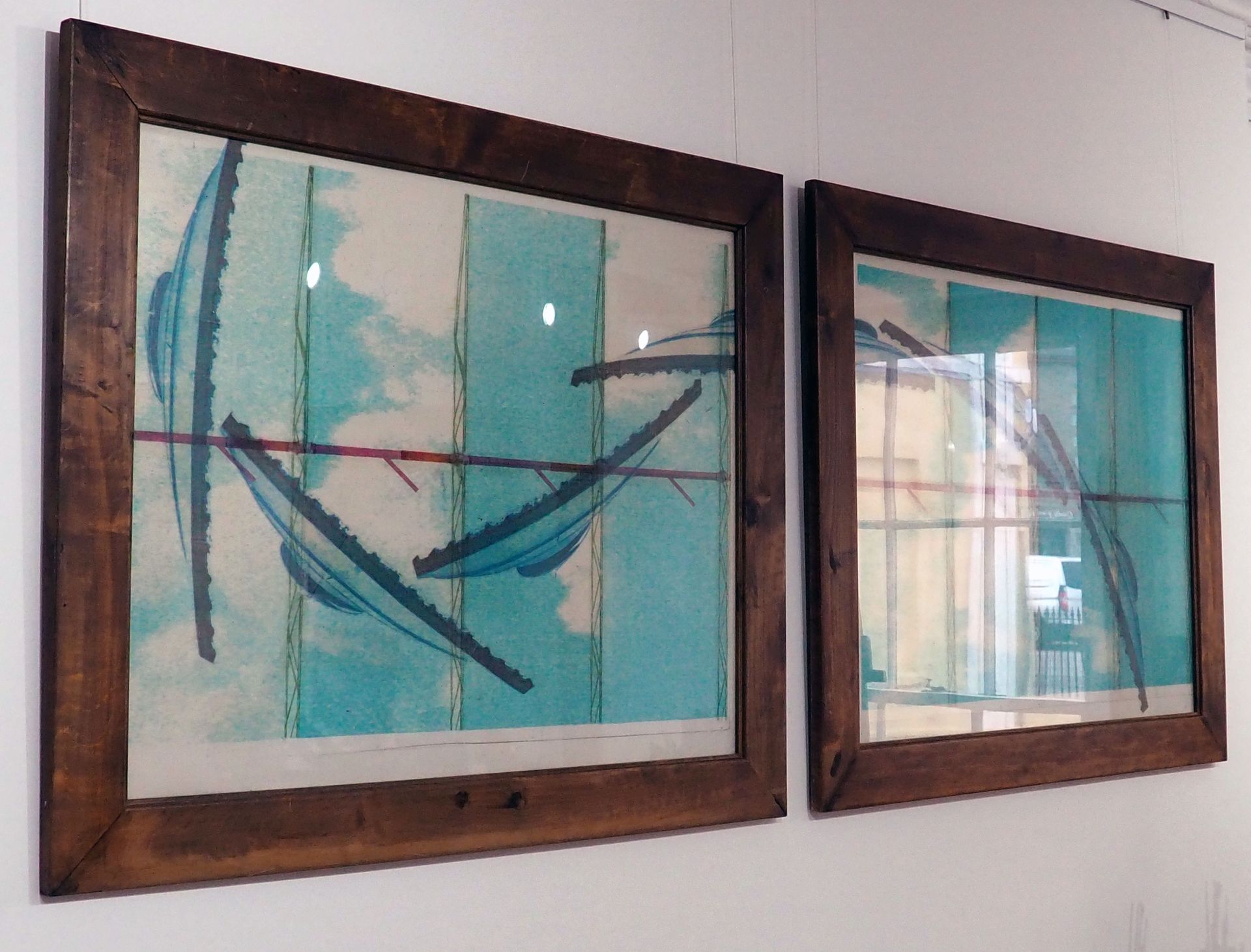 Photo taken from the side of two large framed print-influenced pieces. The roof of the Roundhouse is repeated like a wave in dark blue, and flows from one frame into the other. There are signs of the elevated railway in red as well as the light blue sky as a backdrop.