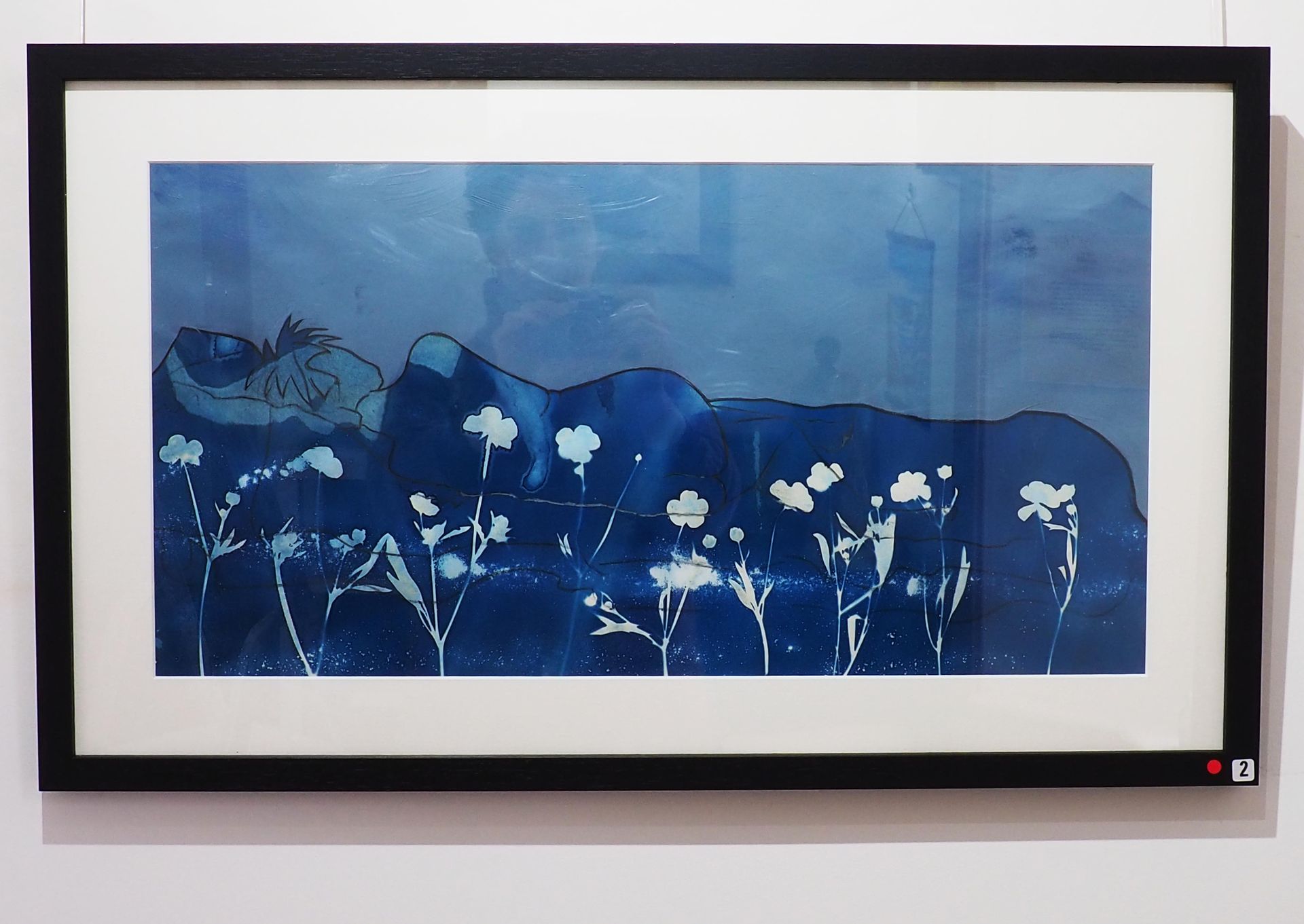 A cyanotype landscape on a grey / blue background. Landscape is formed from a simplistic line drawing of a naked person. There are white masked buttercups in the blue foreground