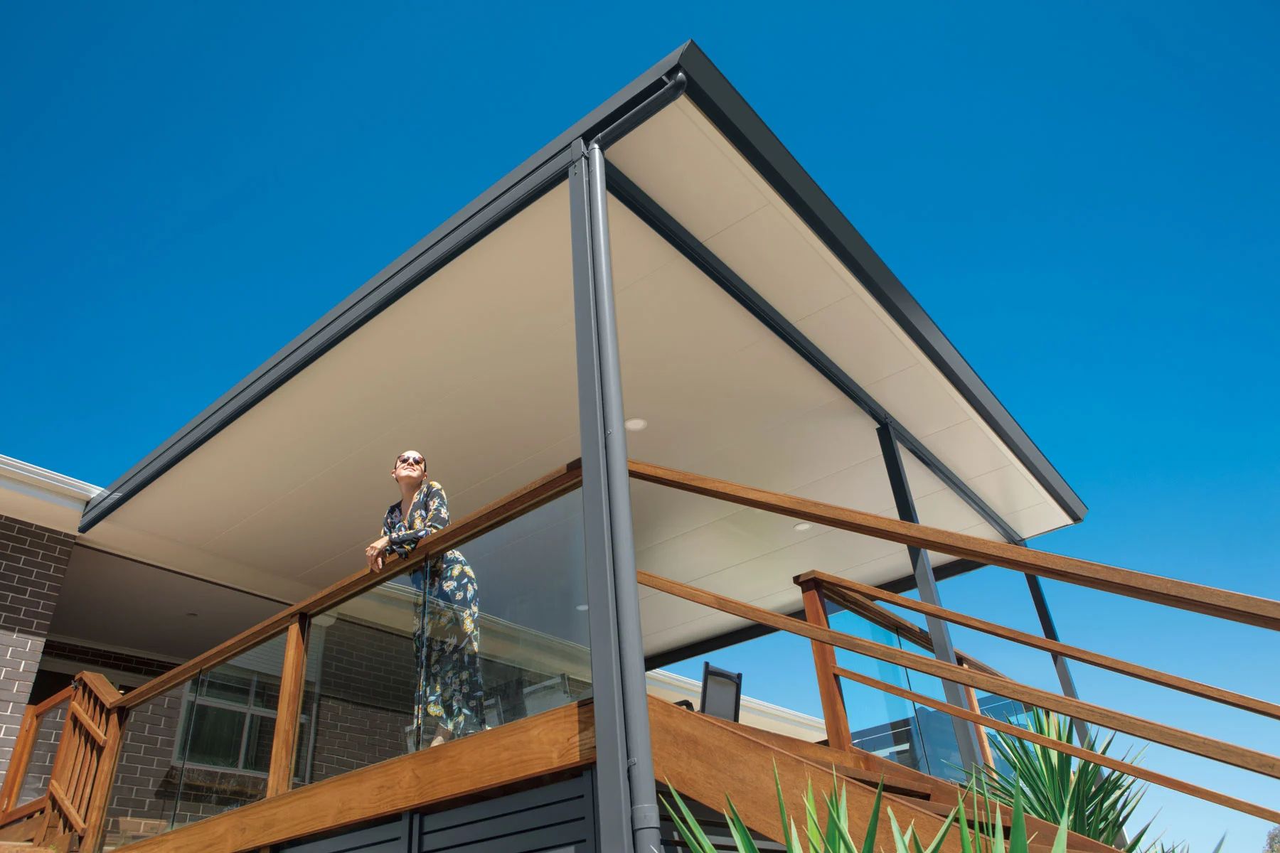 Modern house balcony with a bird perched on the railing under a large overhanging roof
