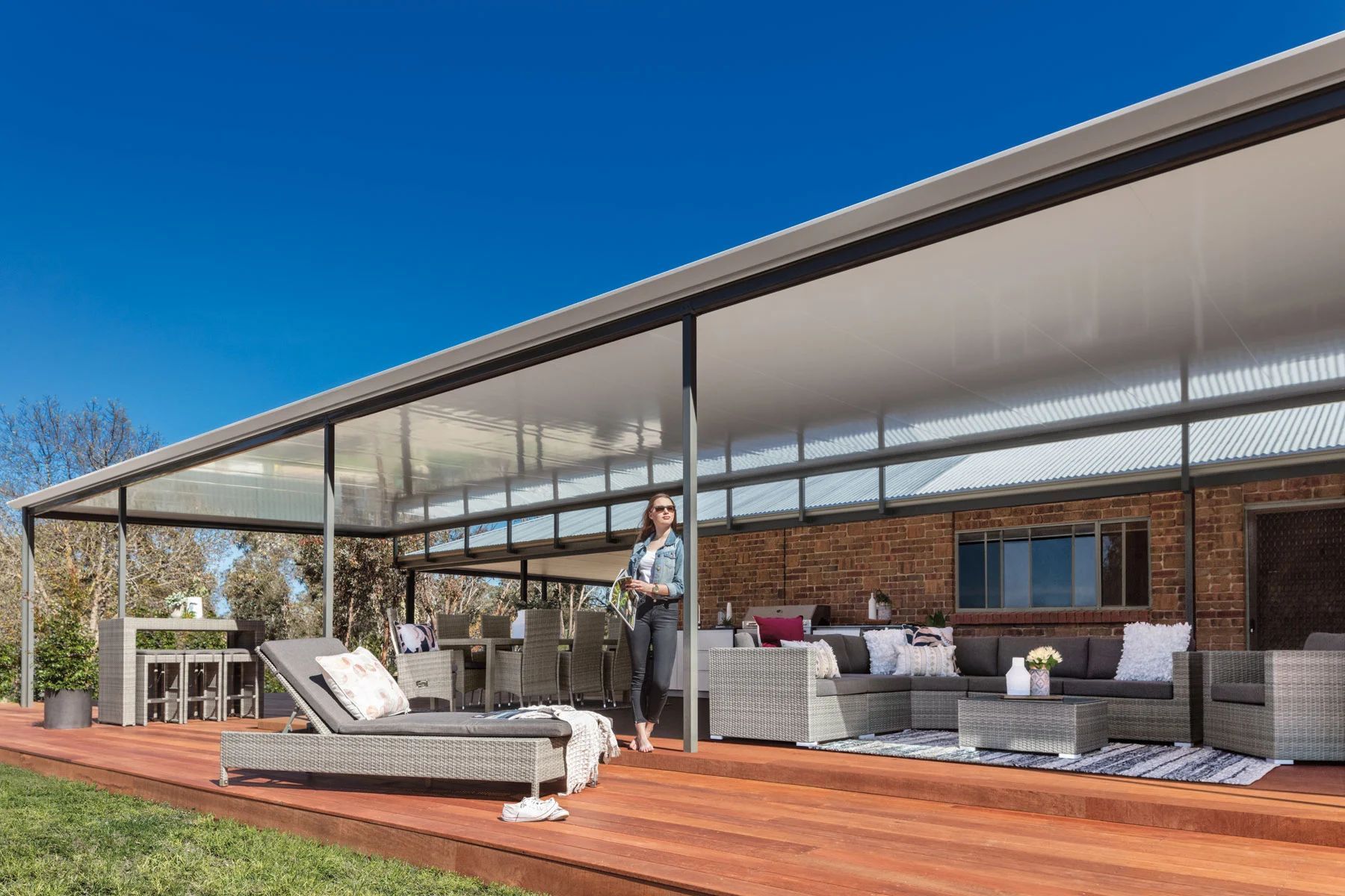 Modern covered patio with outdoor seating and wooden deck under a clear blue sky