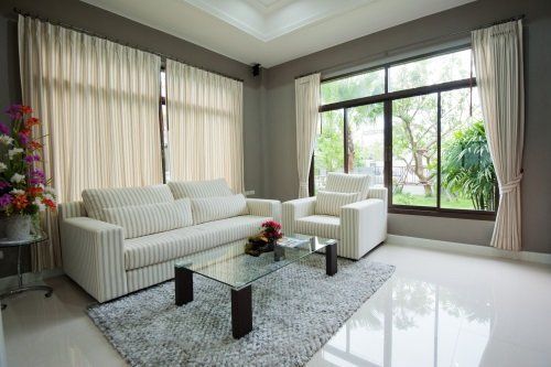 un salotto con un divano e una poltrona di color bianco e un tavolino di vetro