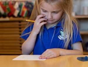 Young child concentrates while writing, developing early handwriting skills
