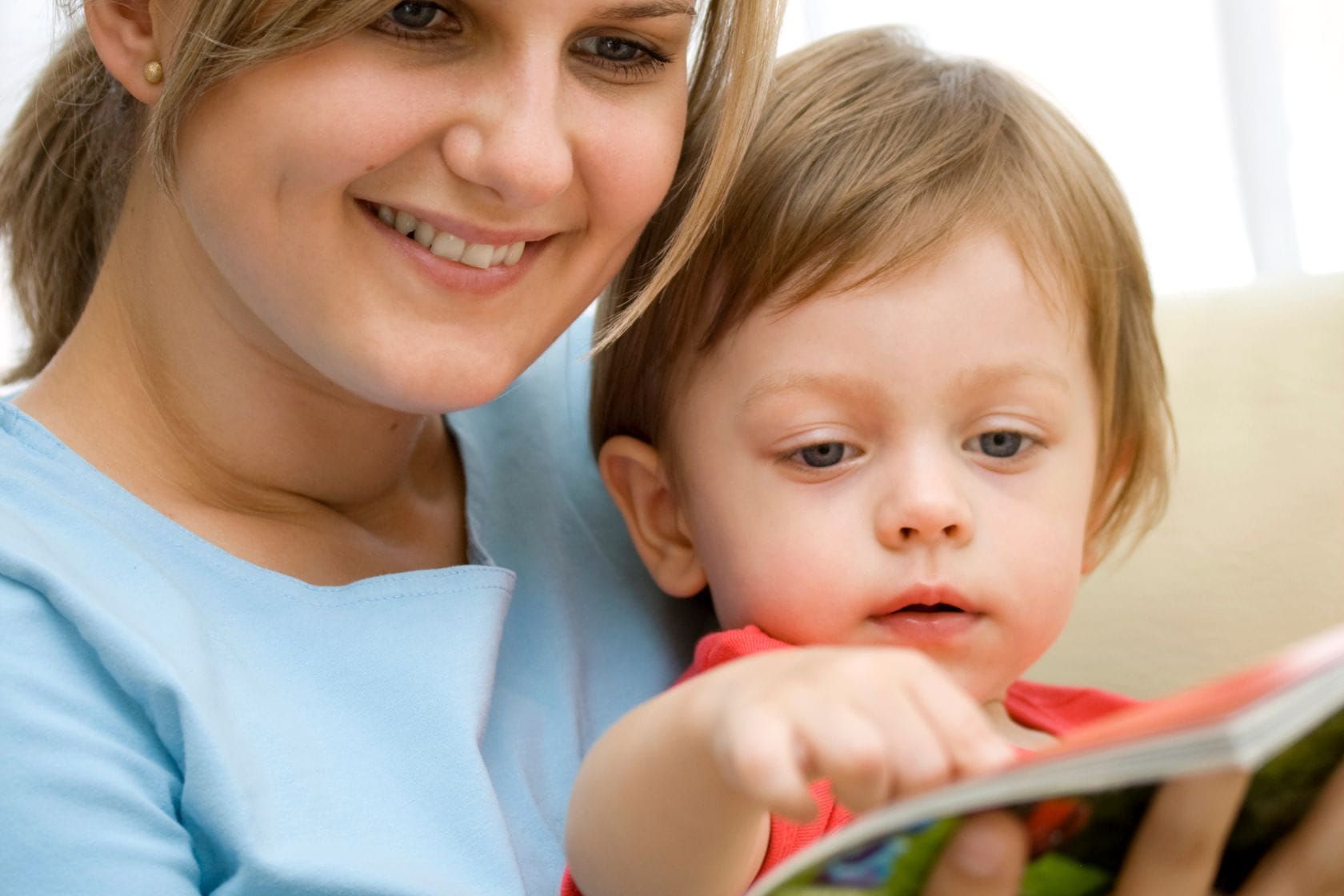 Adult reading a picture book with a child, encouraging curiosity through shared reading.
