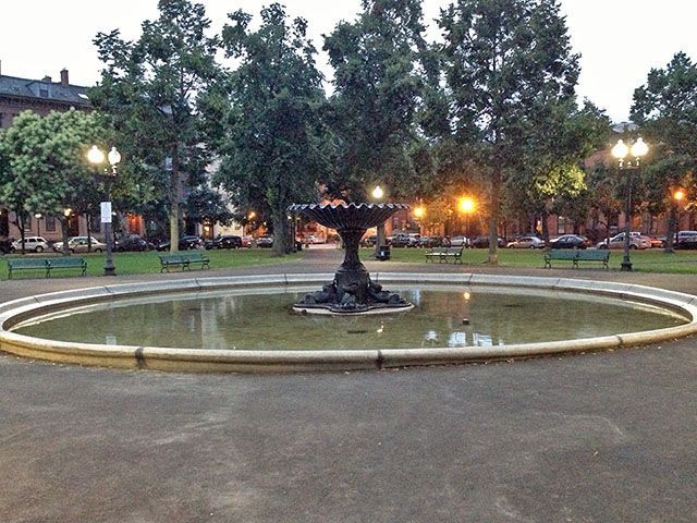 A fountain in a park with trees in the background