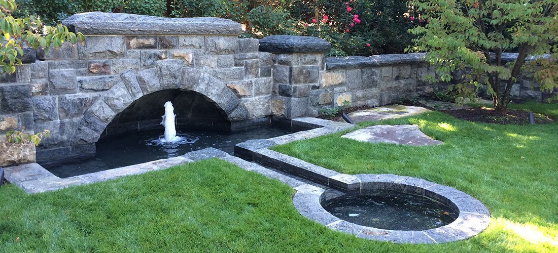 A stone bridge with a fountain in the middle of it.