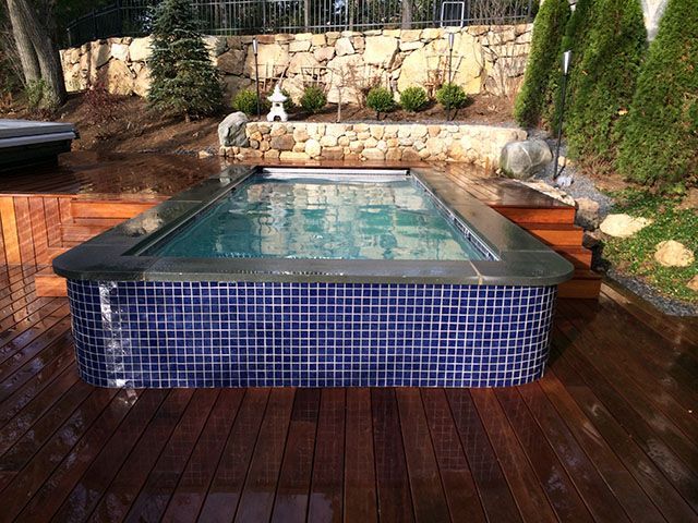A large swimming pool is sitting on a wooden deck
