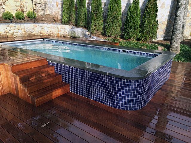 A large swimming pool is sitting on top of a wooden deck.