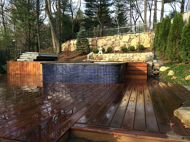 A wooden deck with a swimming pool in the background.