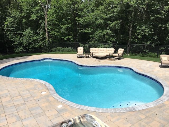 A large swimming pool with a patio and chairs around it