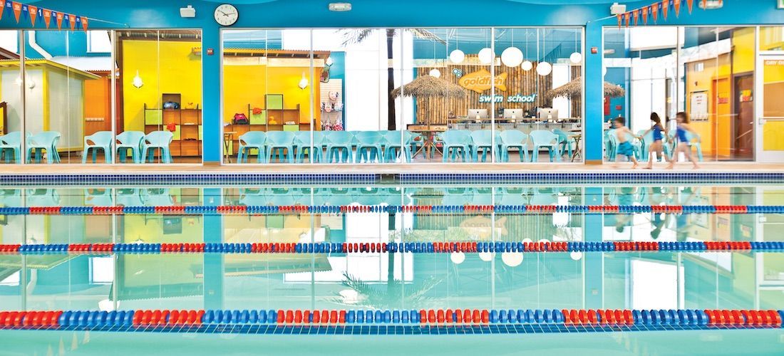 A large swimming pool with a lot of lanes and people swimming in it.