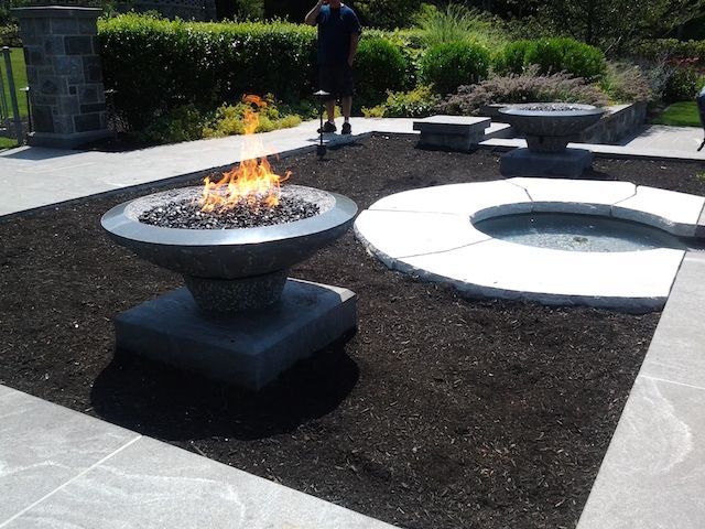 A man stands in front of a fire pit in a garden