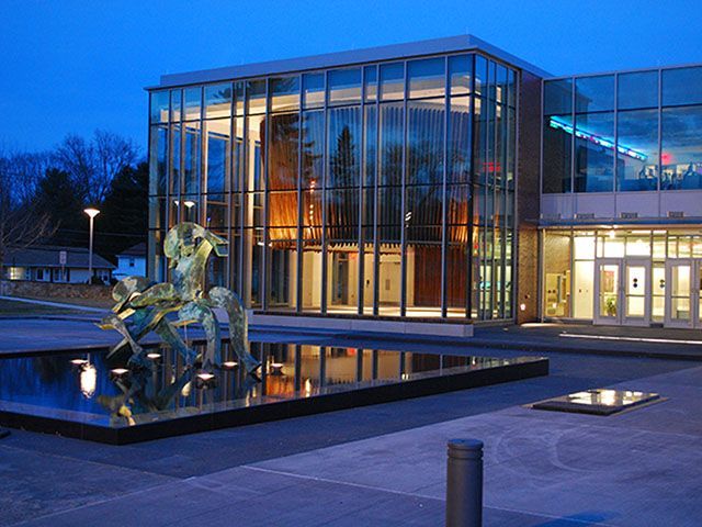 A large glass building with a statue in front of it