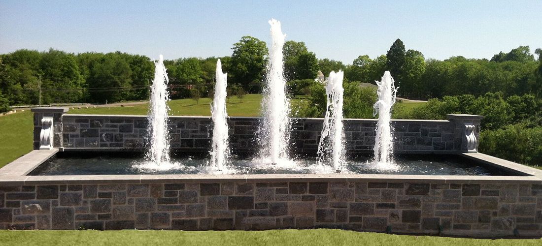 A fountain in a park with trees in the background