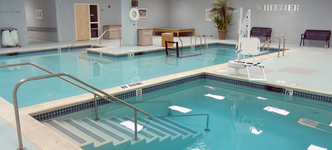 A large indoor swimming pool with stairs leading to it.
