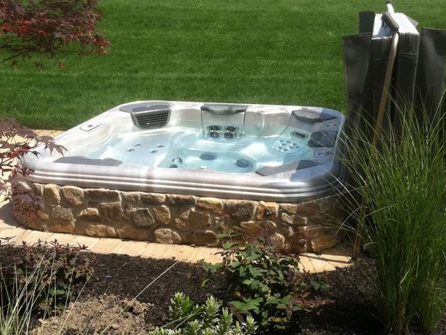 A hot tub is sitting in the middle of a lush green field.